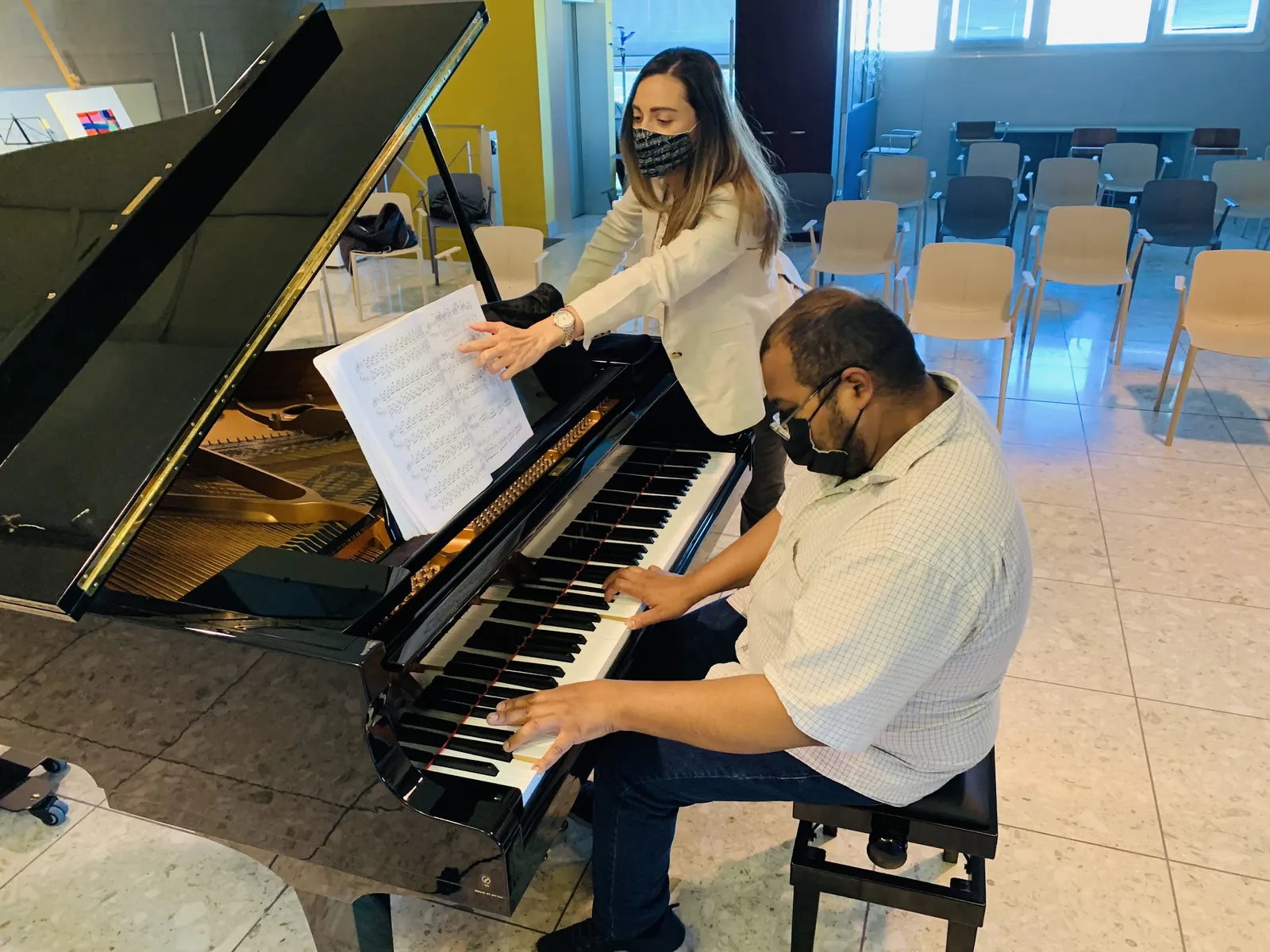 Valentina Dzhegnaradze accanto a un allievo adulto al pianoforte a coda, nello studio di Curno
