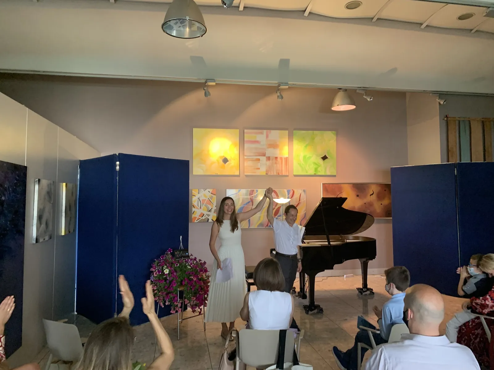 Il saggio nella sala dello studio: il pubblico applaude, Valentina in abito bianco accanto al pianoforte