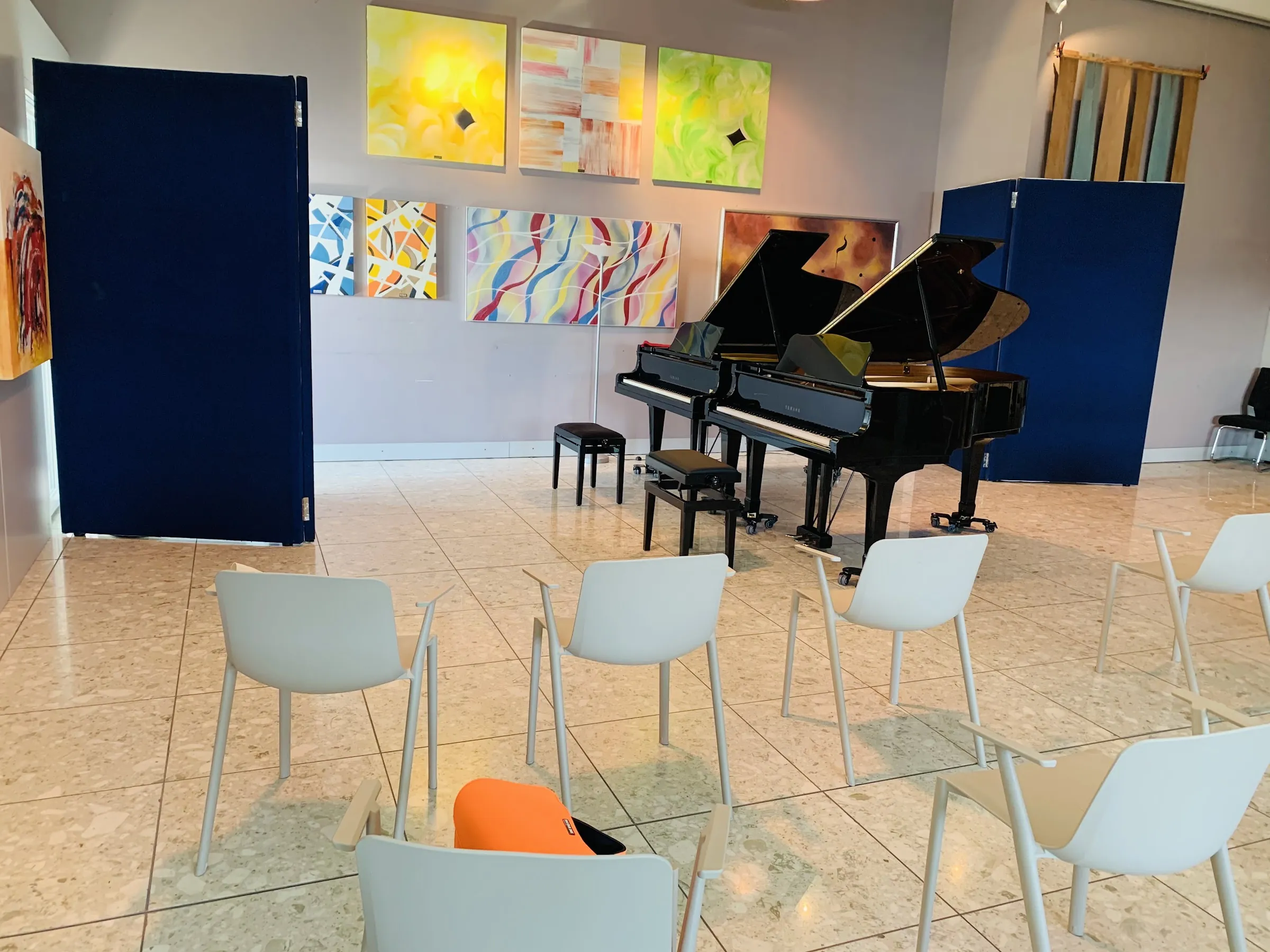 La sala del Piano Studio a Curno: due pianoforti a coda affiancati, i quadri colorati alle pareti, le sedie bianche per il pubblico